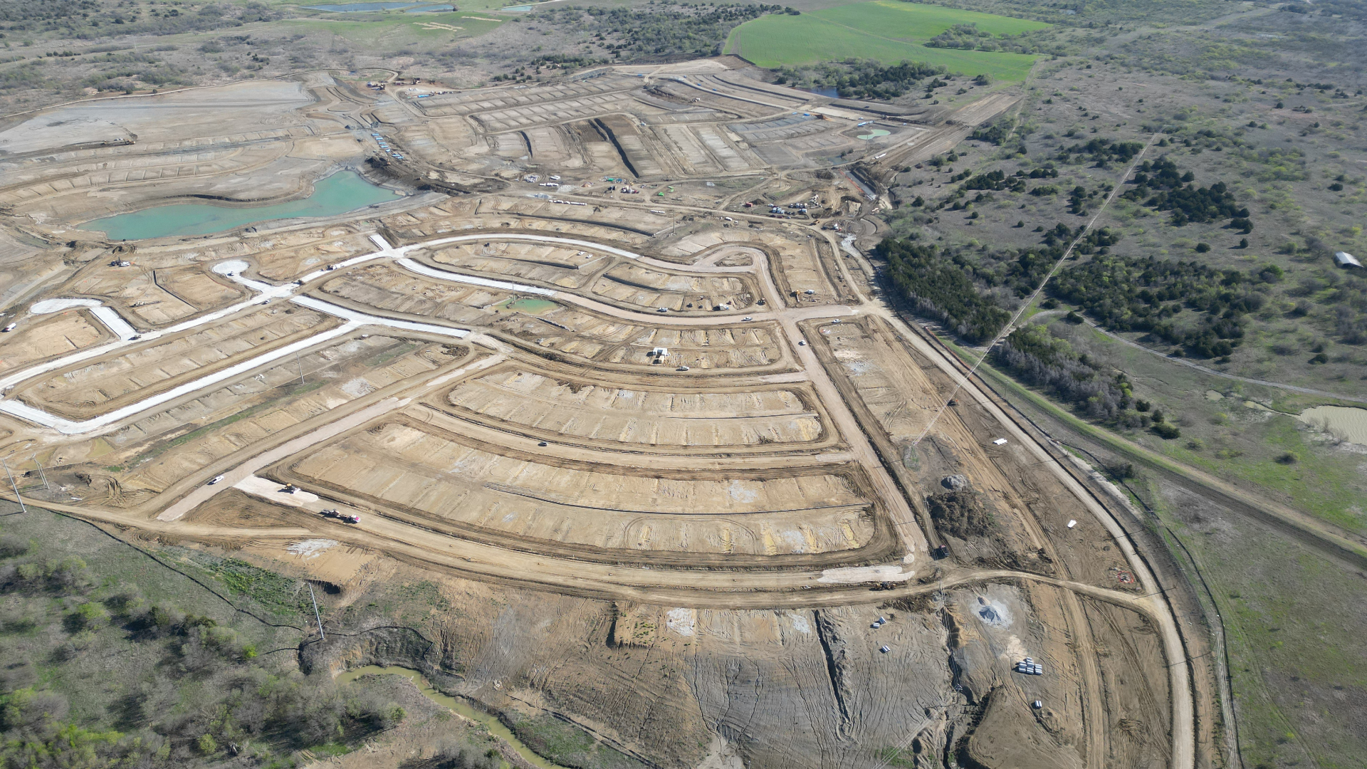 Aerial view of Lakesong Phase 1 site work — graded lots, paved streets, and utilities in progress.